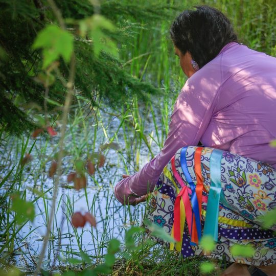 A lady testing the water in a marsh.